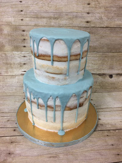2 tier baby shower naked cake with blue drip icing on top.