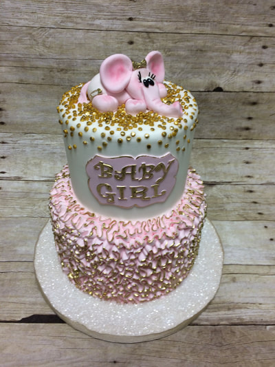2 tier baby shower cake with elephant on top, gold dots and gold brushed pink ruffles on bottom tier.