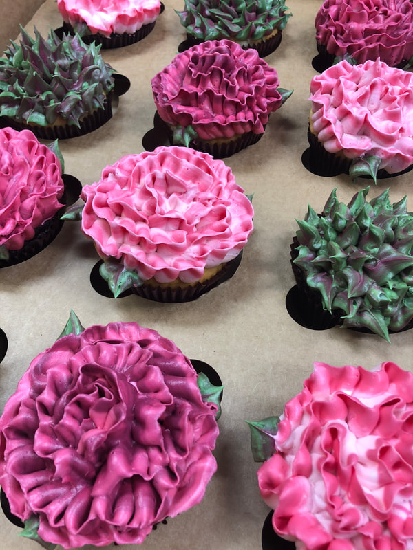 Cupcakes with assorted giant buttercream flowers on top.