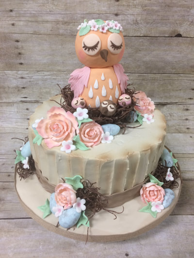 Single tier baby shower cake with an owl on top in a nest with 3 baby owls. Also fondant flowers.