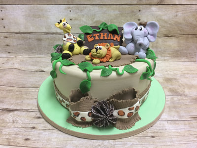 jungle theme boys baby shower cake. with giraffe, lion and elephant and jungle vines and leaves as well as a giant burlap texture fondant bow around cake.