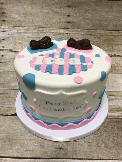 baby shower reveal cake. singe tier, white fondant icing with pink and blue accents.